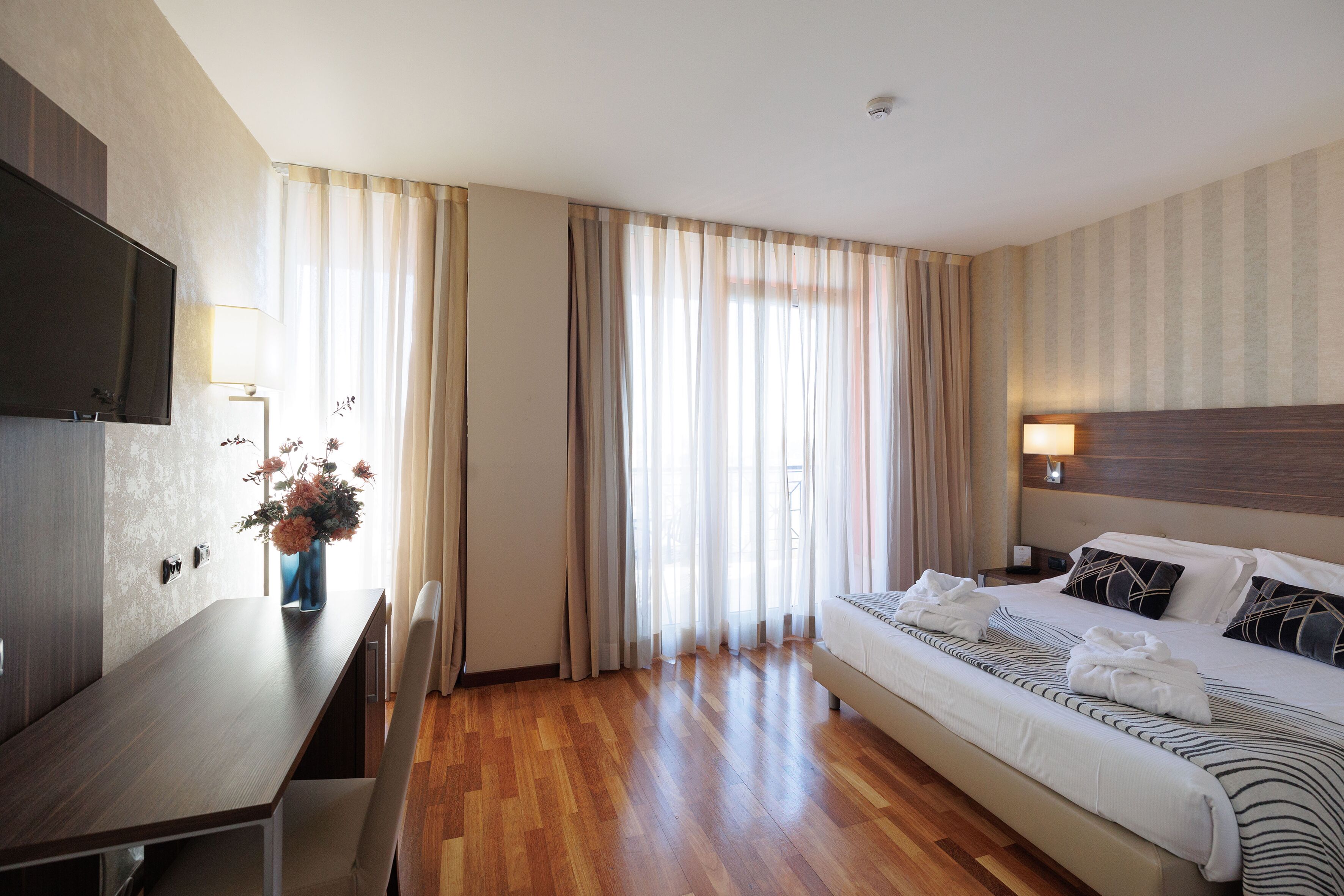 A hotel room with a bed, a desk, and a TV.