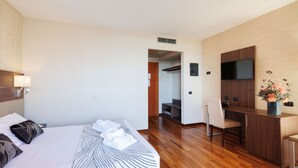 A hotel room with a bed, a desk, a chair, a TV, and a bathroom visible through an open door. - Charme (Prato)