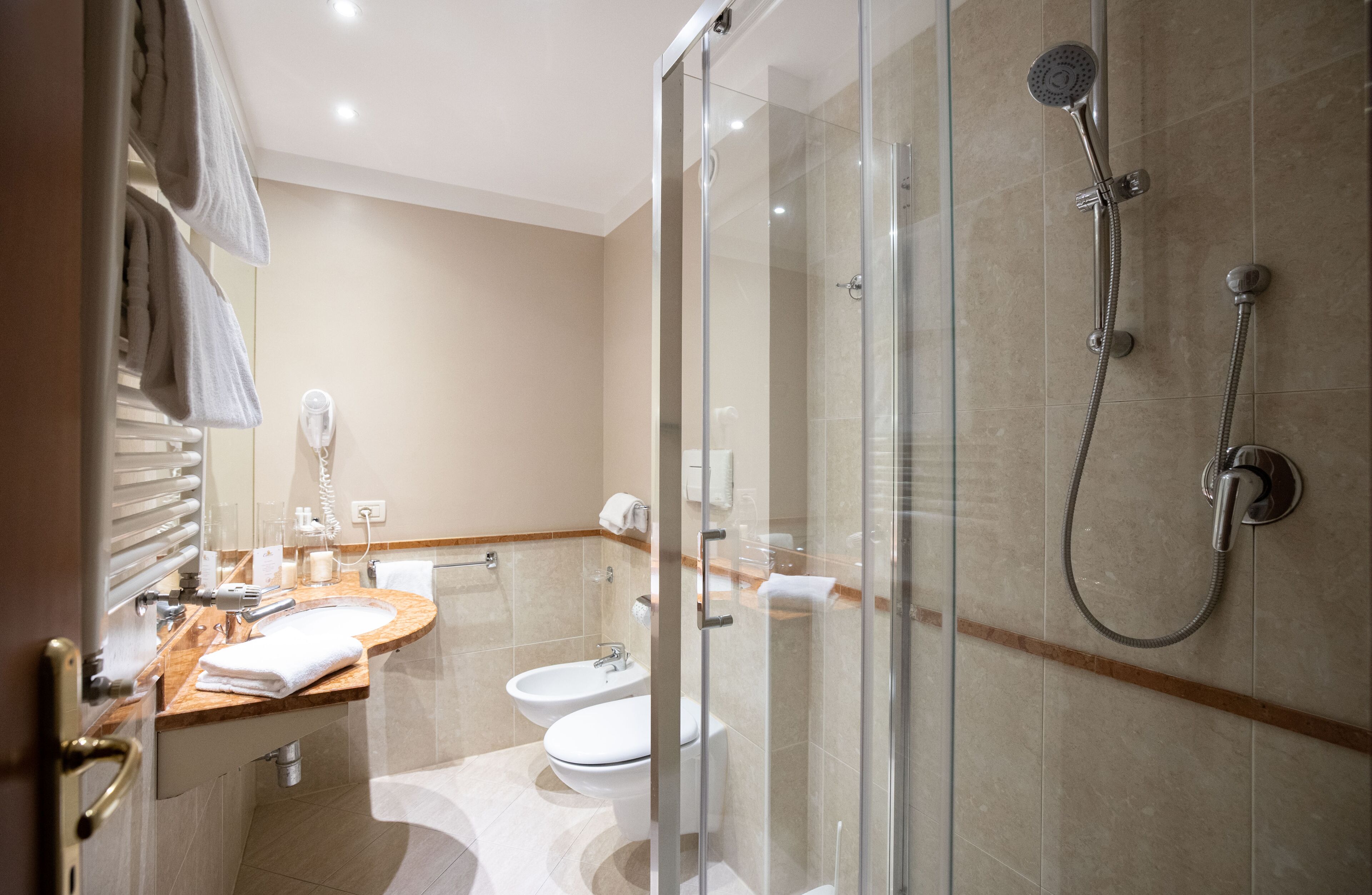 A modern bathroom with a glass-enclosed shower, a wooden vanity, a white sink, and a toilet.