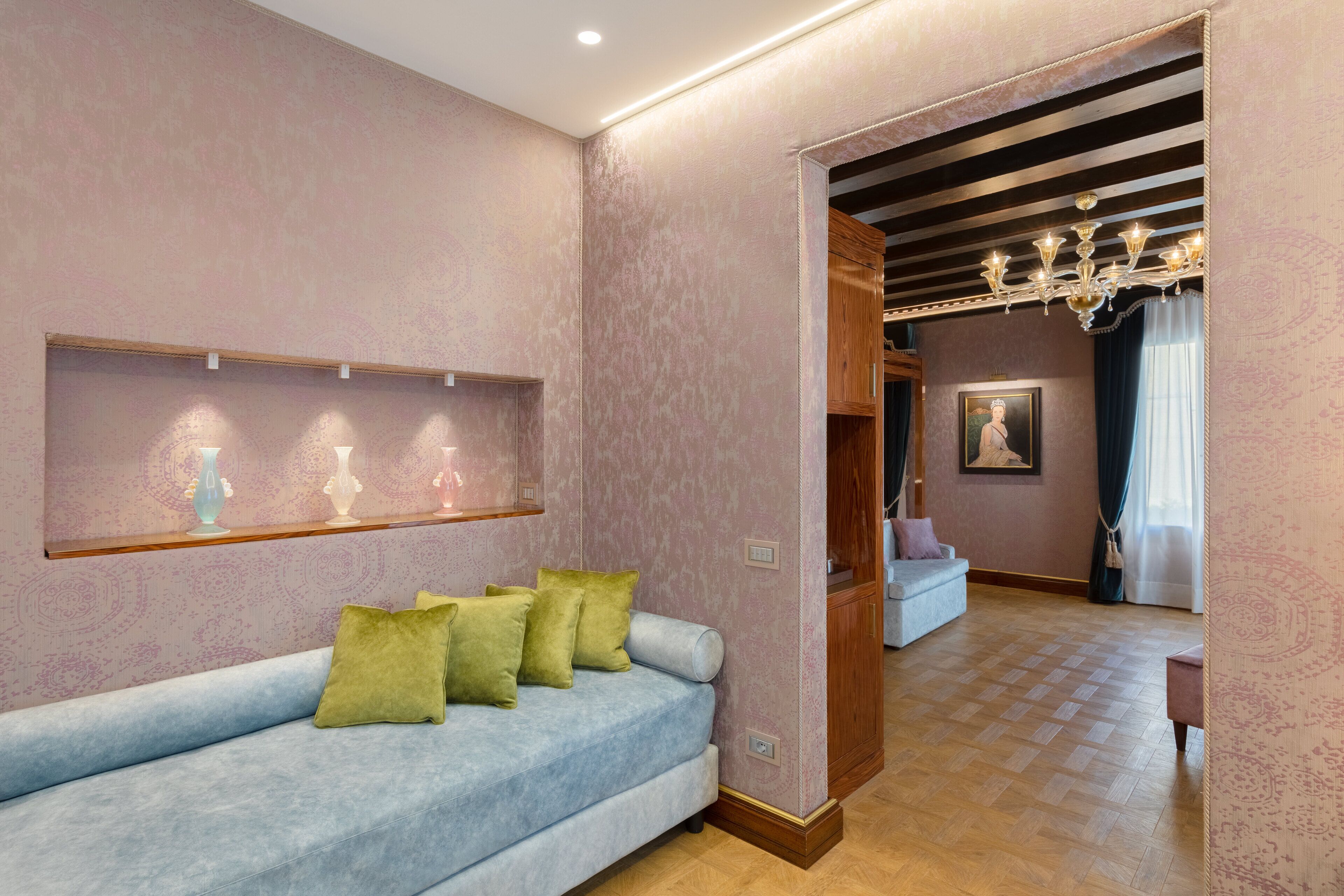 A modern living room with a light blue sofa, green cushions, a wooden cabinet, and a chandelier.