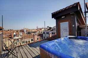 A rooftop terrace with a hot tub, wooden deck, and a view of the cityscape. - Hotel Dona Palace (Venice)