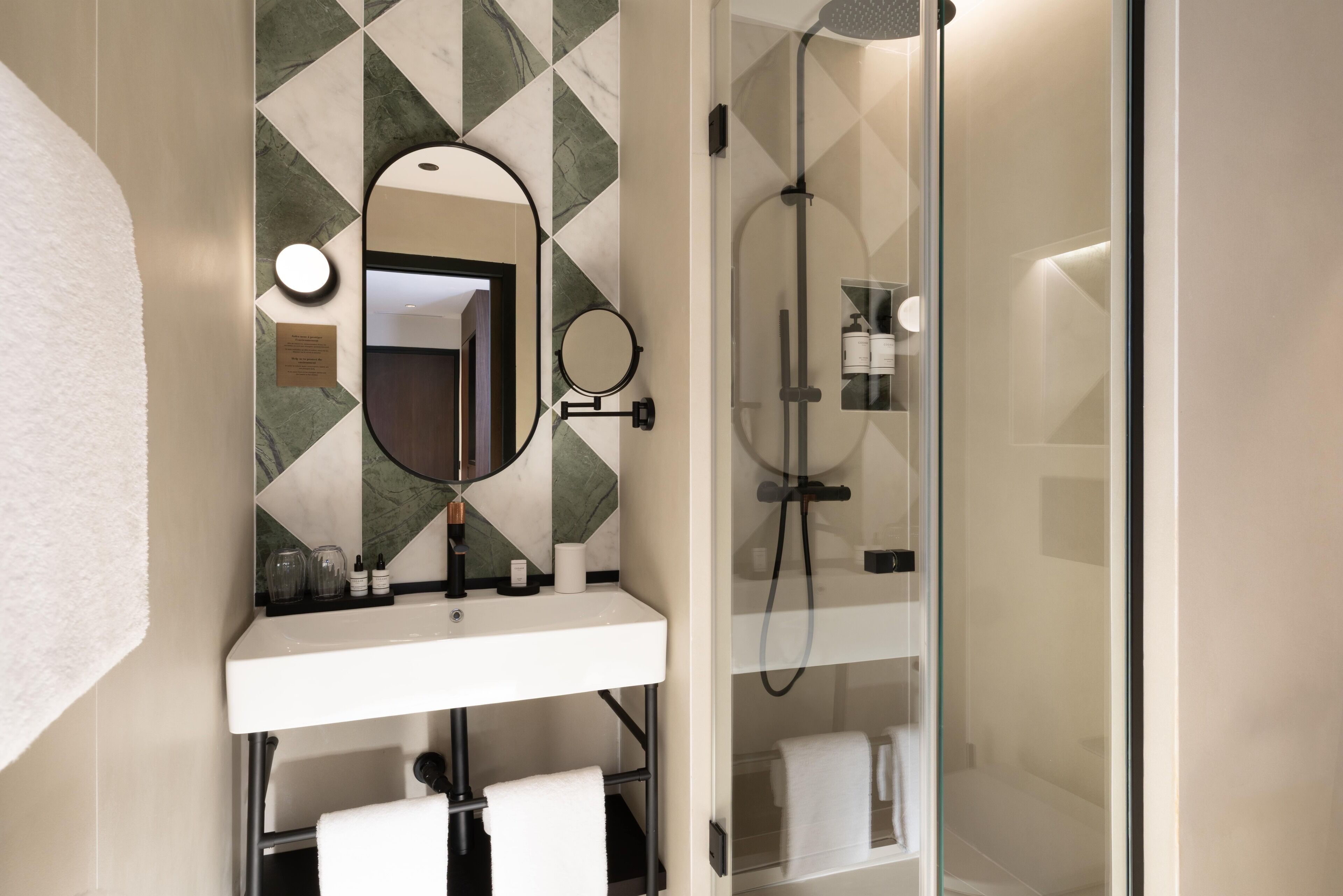 A bathroom with a white sink, a mirror, a shower enclosure, and a towel rack.