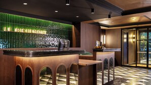 A reception area with a green-lit wall and a check-in counter. - Hôtel Le Richemont (Paris)