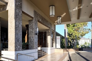 A modern hotel entrance with marble columns, a staircase, and a sign for Riu hotel.