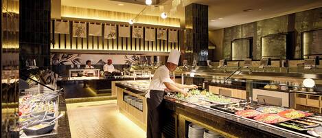 A buffet setup with multiple food stations and a chef preparing food.