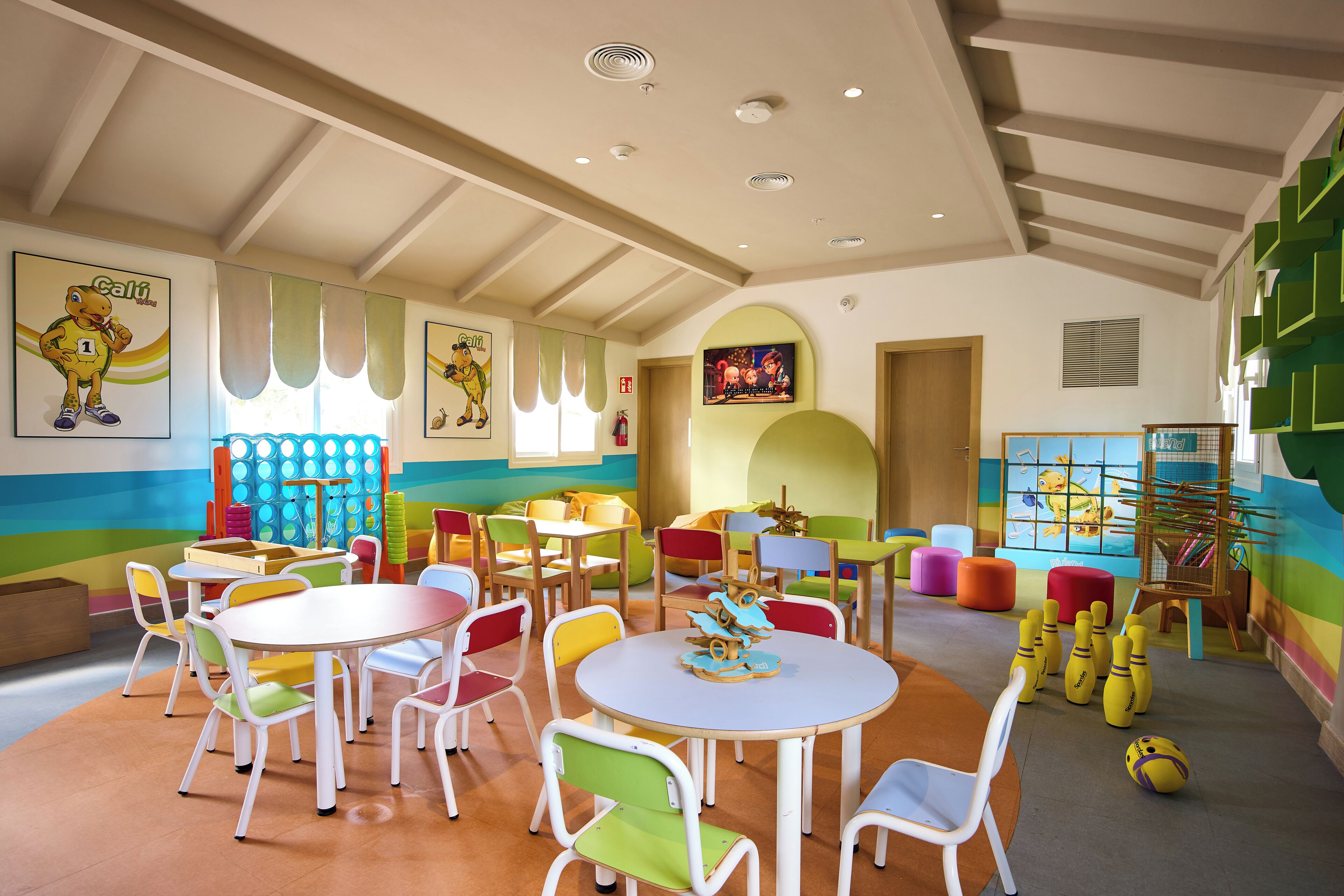 A children's playroom with colorful furniture, a bowling alley, and various play structures.