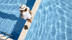 Una piscina con acqua cristallina e una persona in piedi sul bordo.
