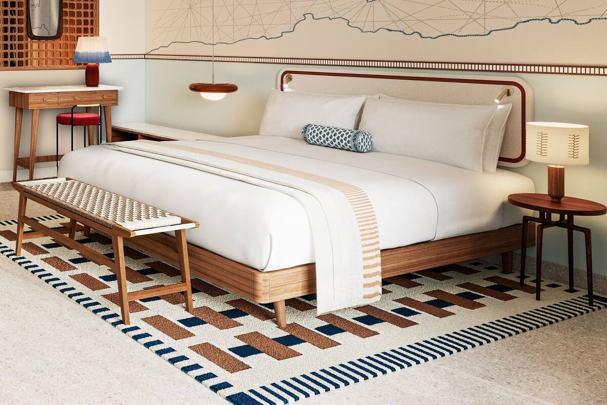 Un dormitorio ordenado con una cama grande, mesitas de noche, un pequeño taburete y un mapa en la pared.