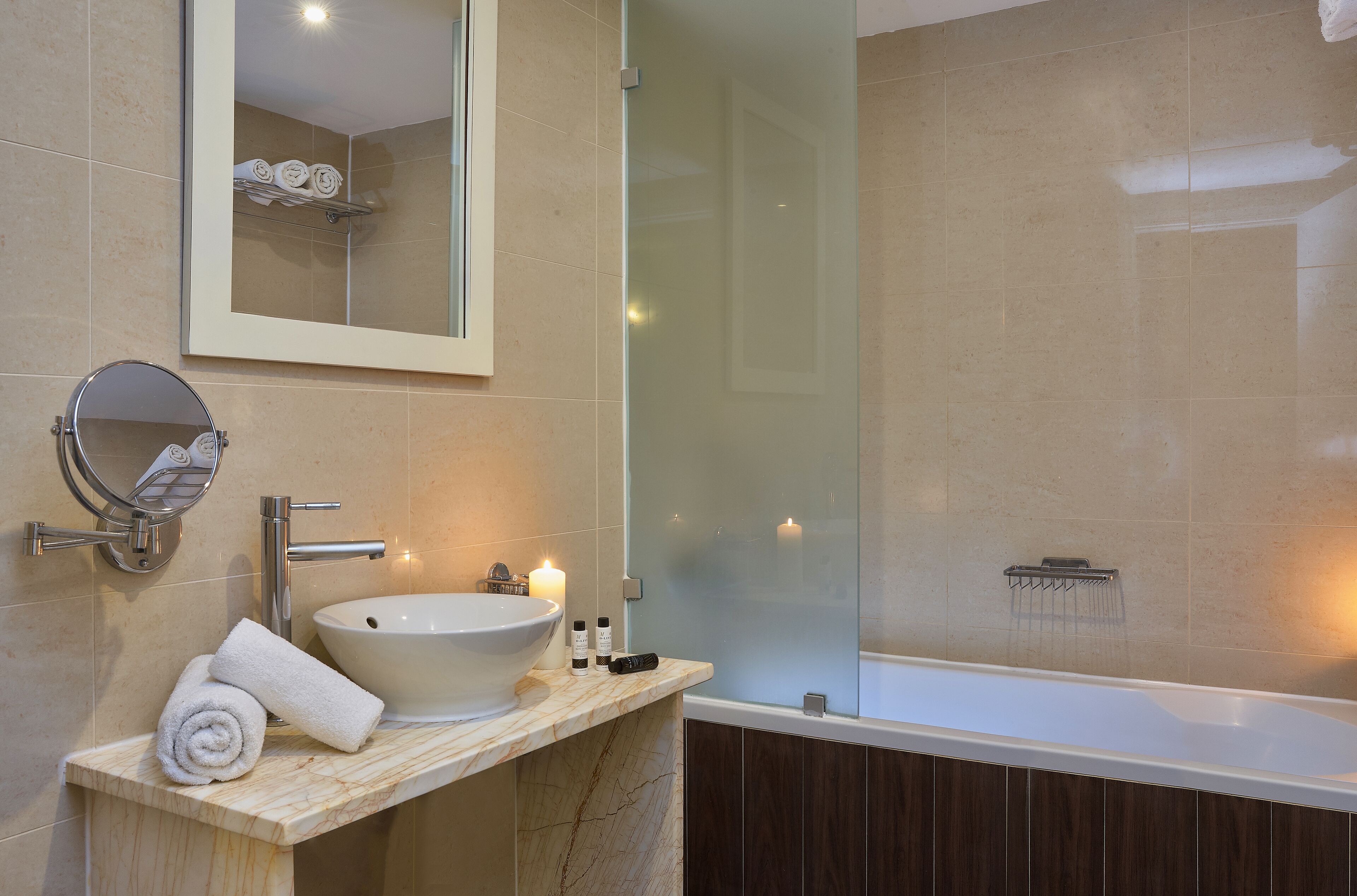 A bathroom with a sink, mirror, and a glass-enclosed shower area.