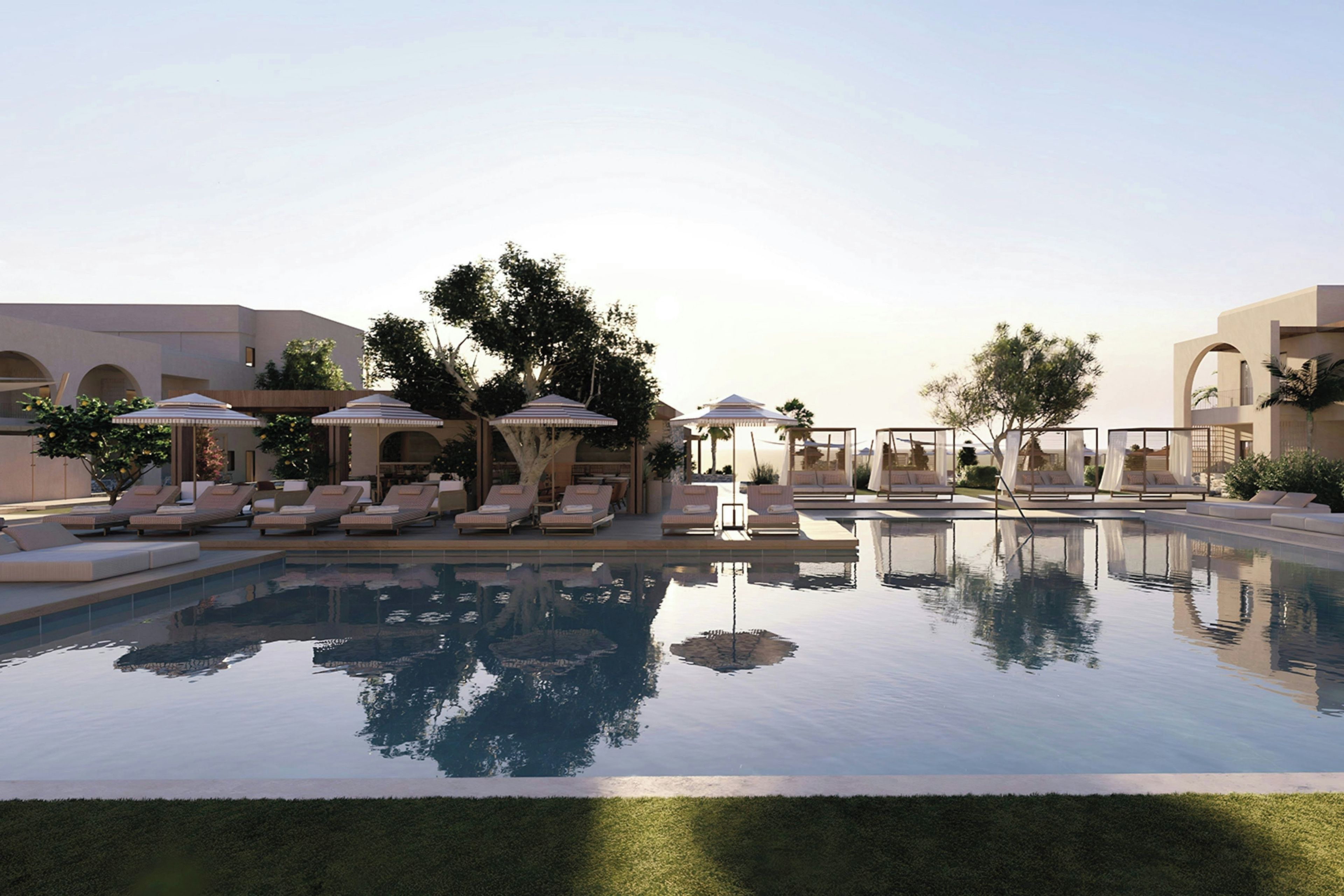 Una piscina con sillones de descanso y sombrillas, rodeada de árboles y arquitectura moderna.