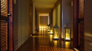 Un corridoio d'albergo con pavimento in legno, pareti decorate e lanterne a parete.