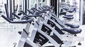 A row of stationary bikes in a gym with mirrored walls.