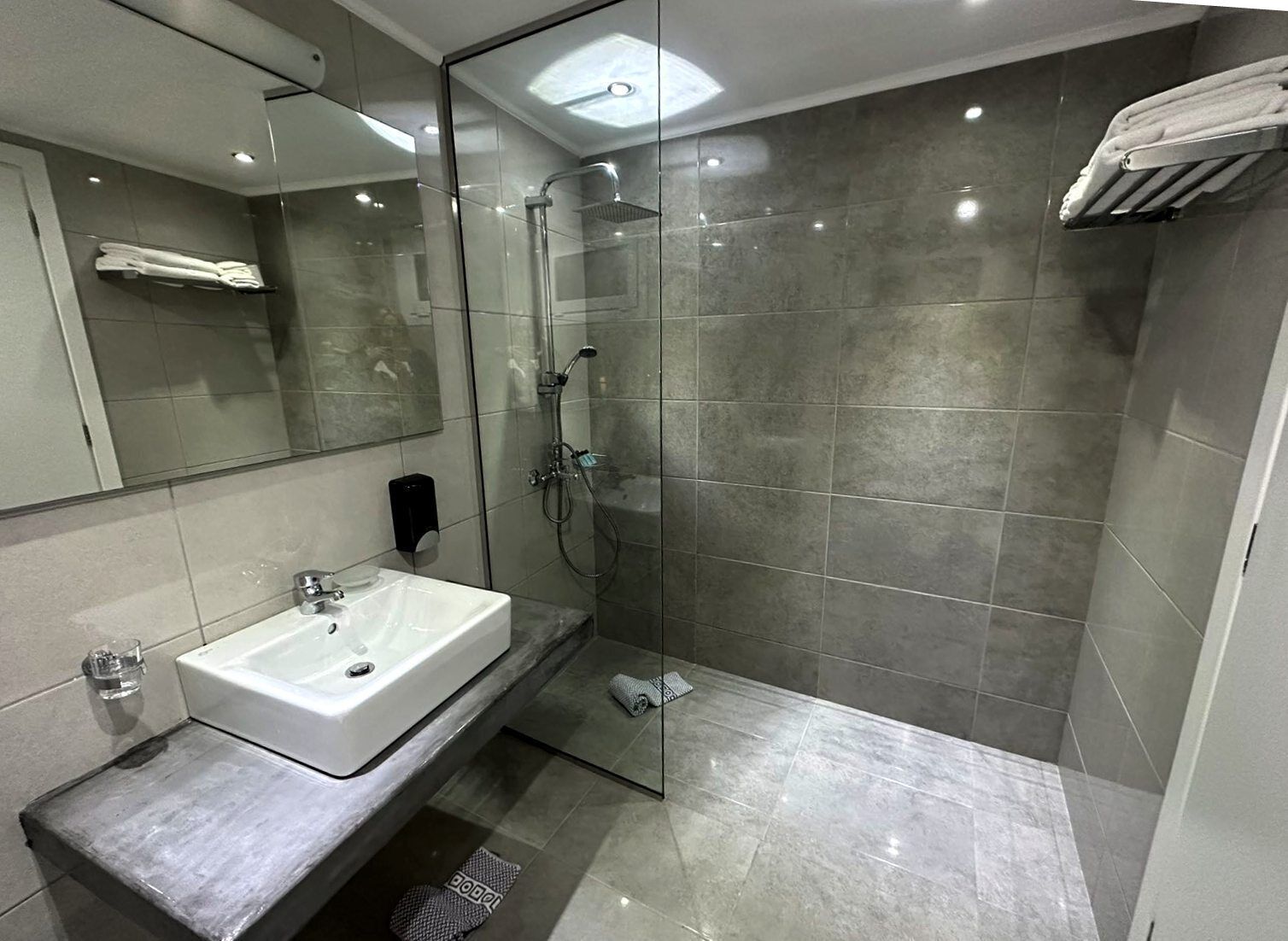 A modern bathroom with a glass-enclosed shower, a white sink, and a towel rack.