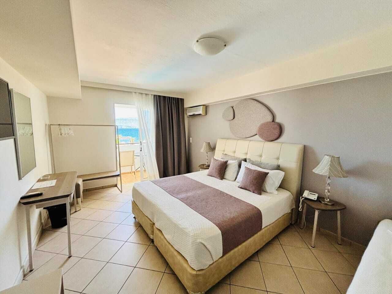 Een hotelkamer met een bed, nachtkastjes, een bureau en uitzicht op de omgeving.
