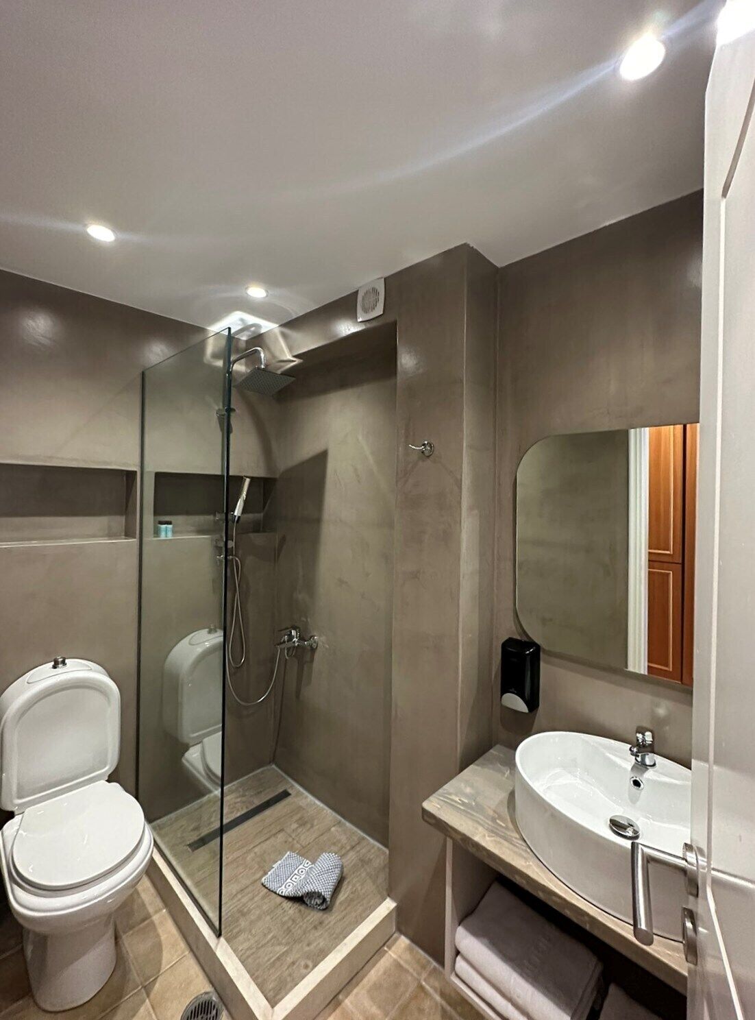 Un baño moderno con ducha envuelta en vidrio, inodoro y lavamanos.