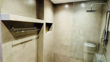 A modern bathroom with a glass-enclosed shower, a toilet, and a sink.