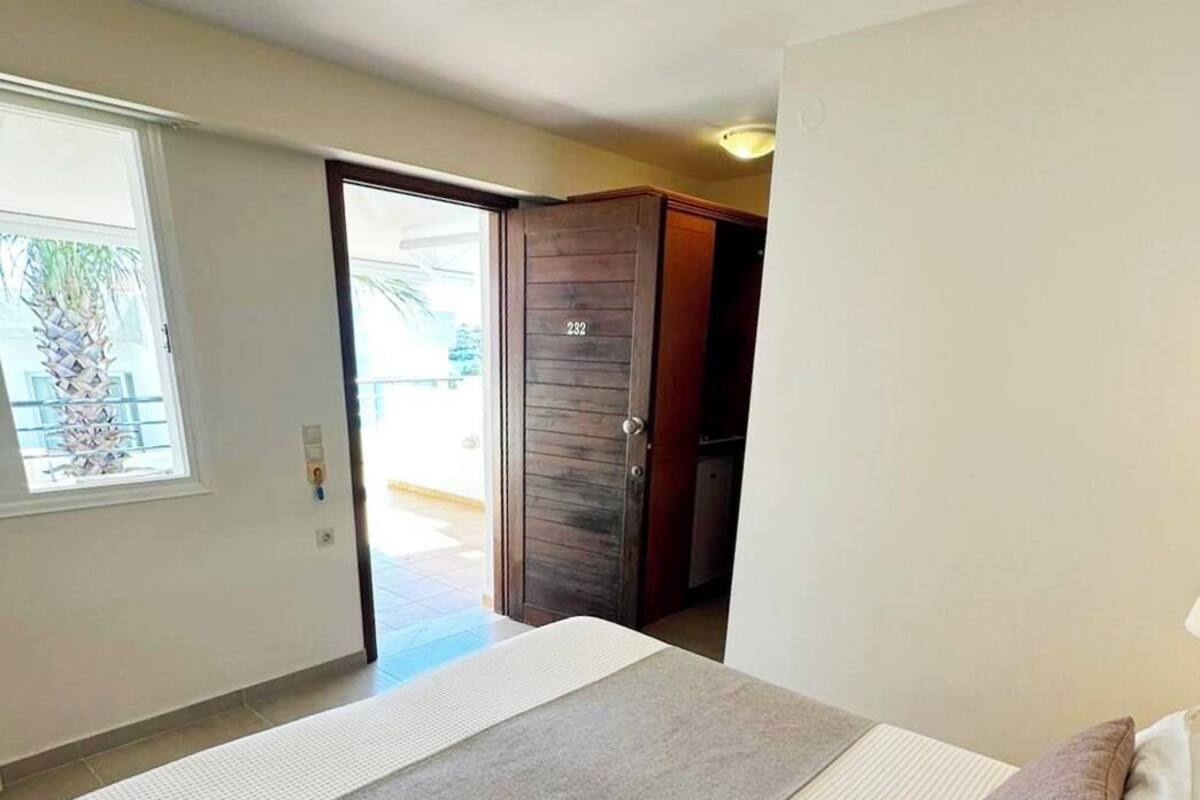 Habitación de hotel con una cama grande, un ventanal con vistas y una puerta que da a un balcón.