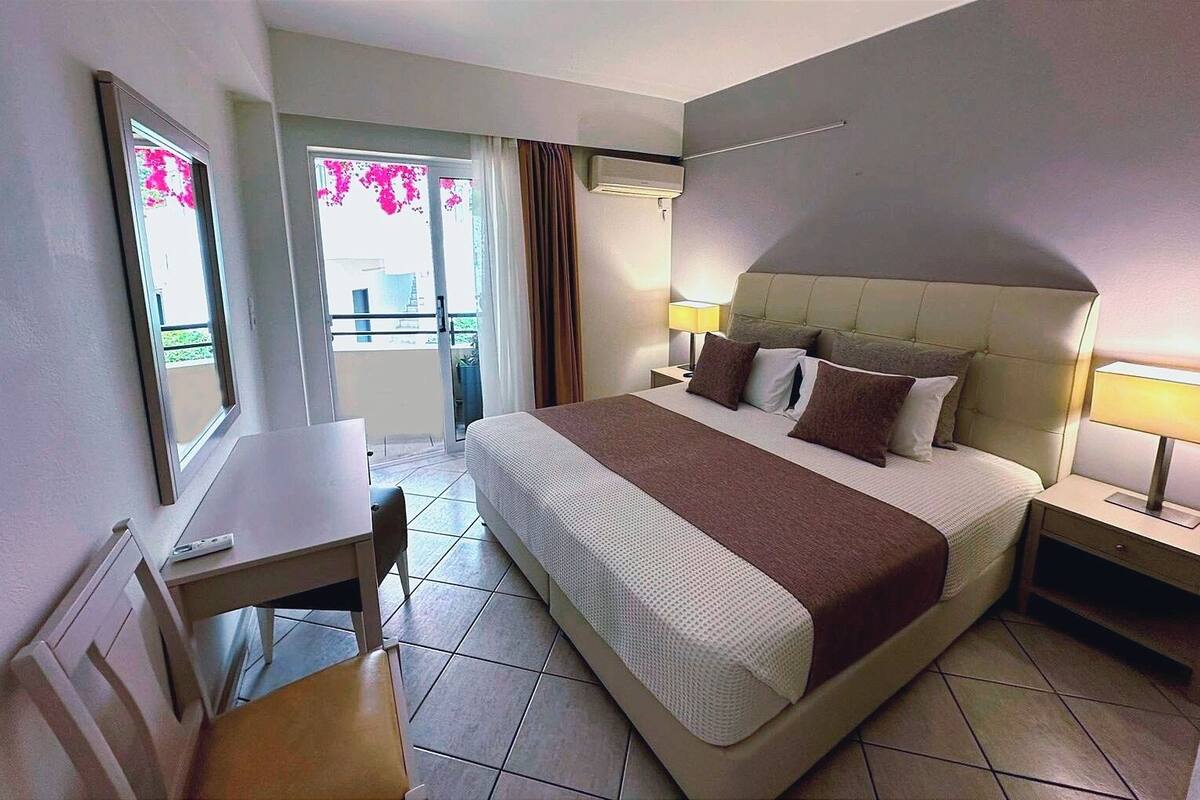 Una habitación de hotel con una cama, mesitas de noche, un escritorio y una silla.
