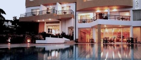 A multi-story hotel with a pool in the foreground.