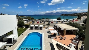 A pool area with lounge chairs and a view of the sea. - Faedra Beach Hotel (Agios Nikolaos)