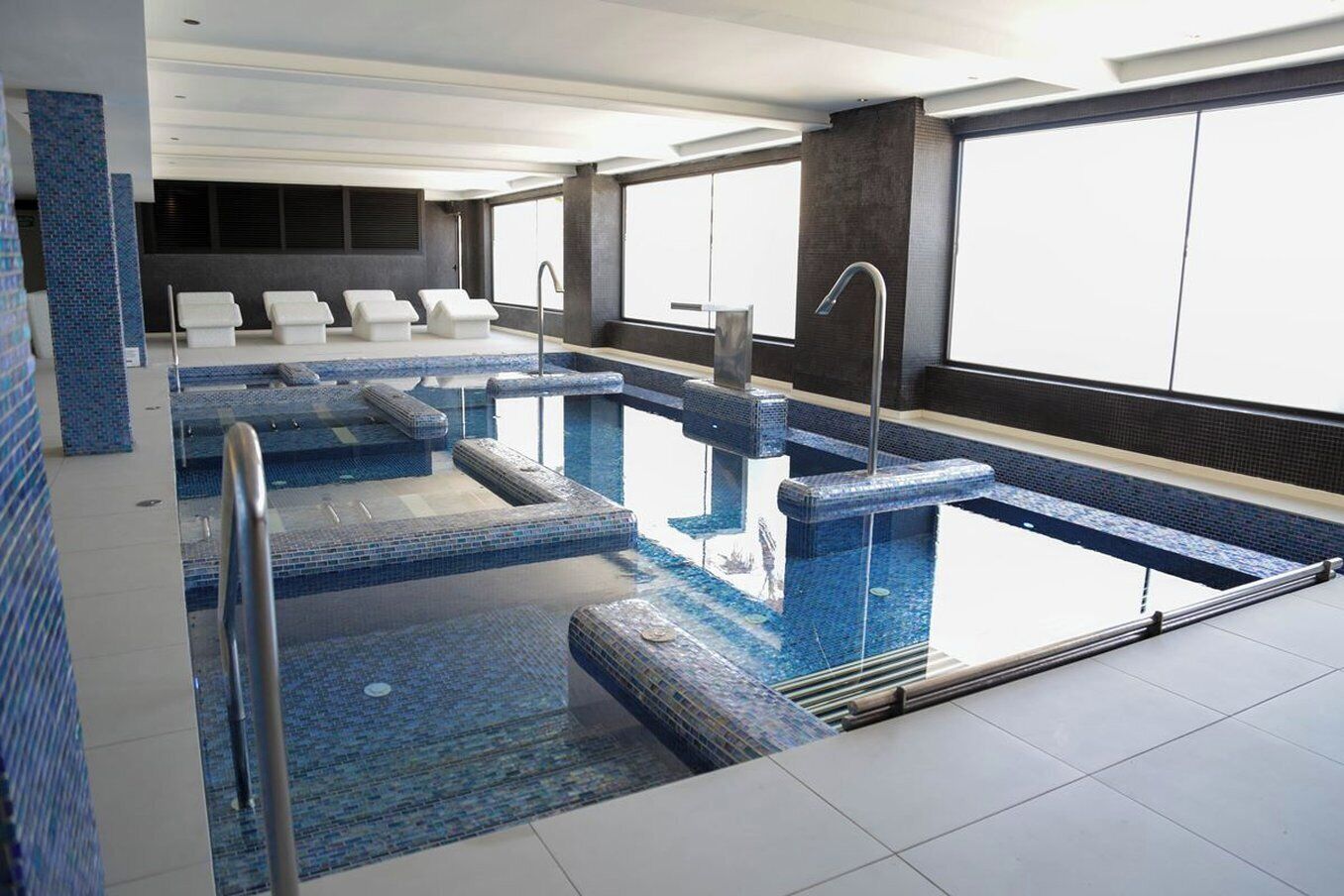 Una piscina interior moderna con varias pistas, agua cristalina y suelo de baldosas.