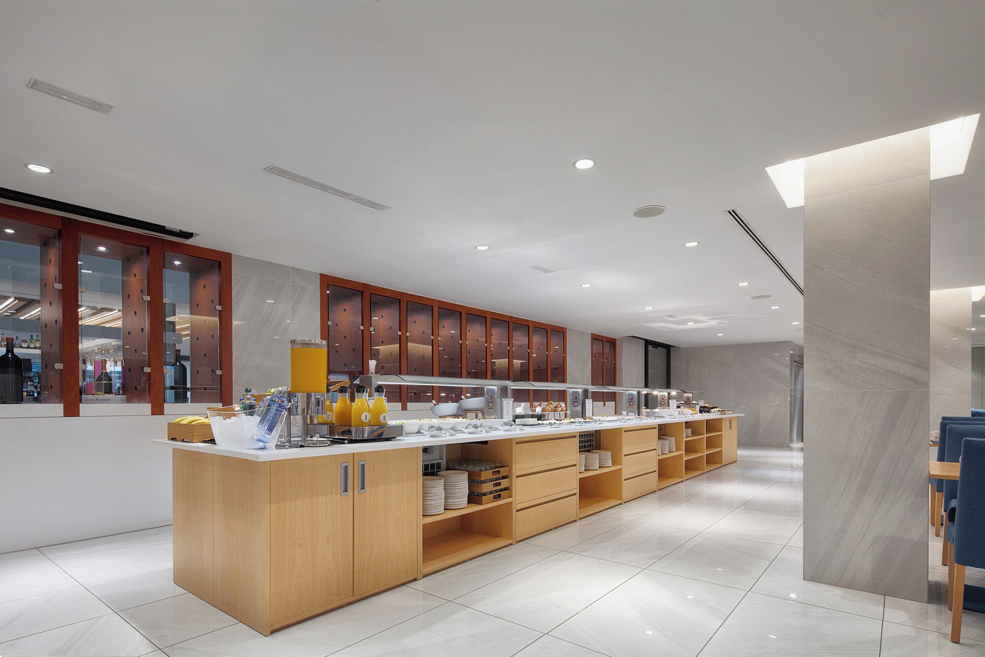 A modern breakfast bar with a wooden counter, glass doors, and a tiled floor.