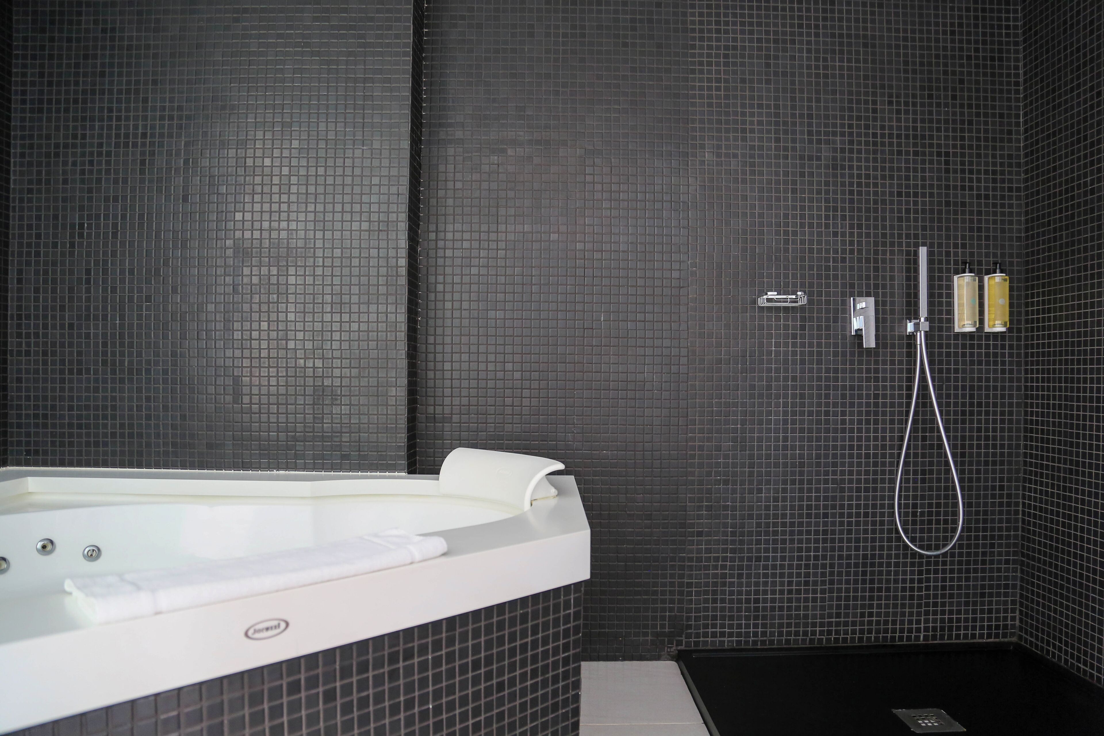 Un baño moderno con una bañera grande, un cabezal de ducha de mano y un grifo instalado en la pared.