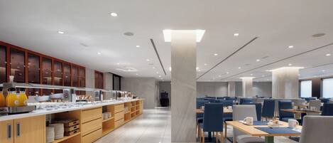 A modern cafe with a long counter, seating area, and a large pillar.