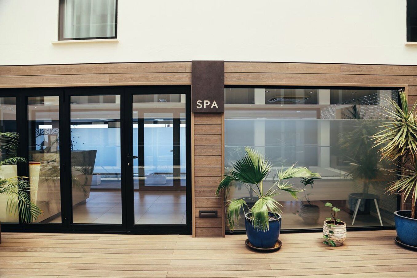 A spa with a modern design, featuring large glass doors and potted plants outside.