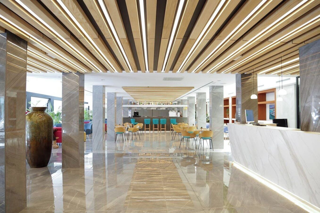 Un moderno vestíbulo de hotel con un mostrador de recepción, zona de estar y un gran jarrón.