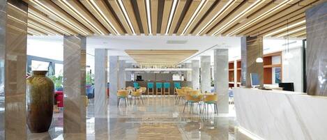 Un moderno vestíbulo de hotel con un mostrador de recepción, zona de estar y un gran jarrón.