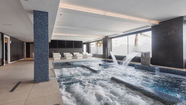 A spa area with a hot tub, seating, and a view of the outdoors.