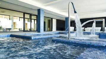 A modern indoor pool area with a hot tub and a water fountain.