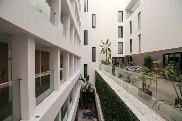 A modern building with multiple floors, glass railings, and indoor plants. - Eurostars Puerto de Ibiza (Ibiza Town)