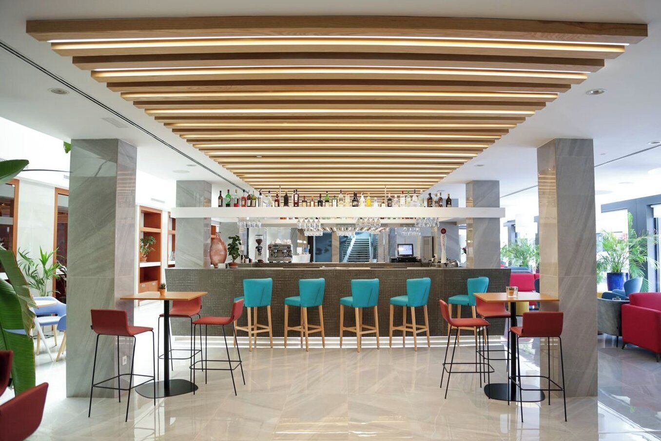 Zona de bar moderna con techo de madera, taburetes y una barra con diferentes botellas.