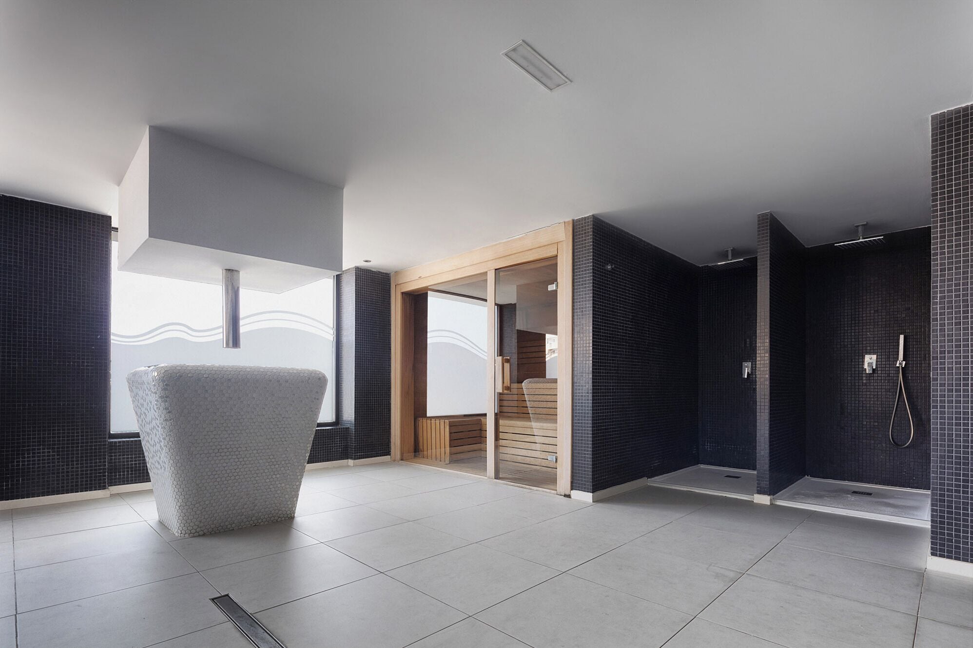 A modern bathroom with a large mirror, a shower area, and a seating area with a chair.