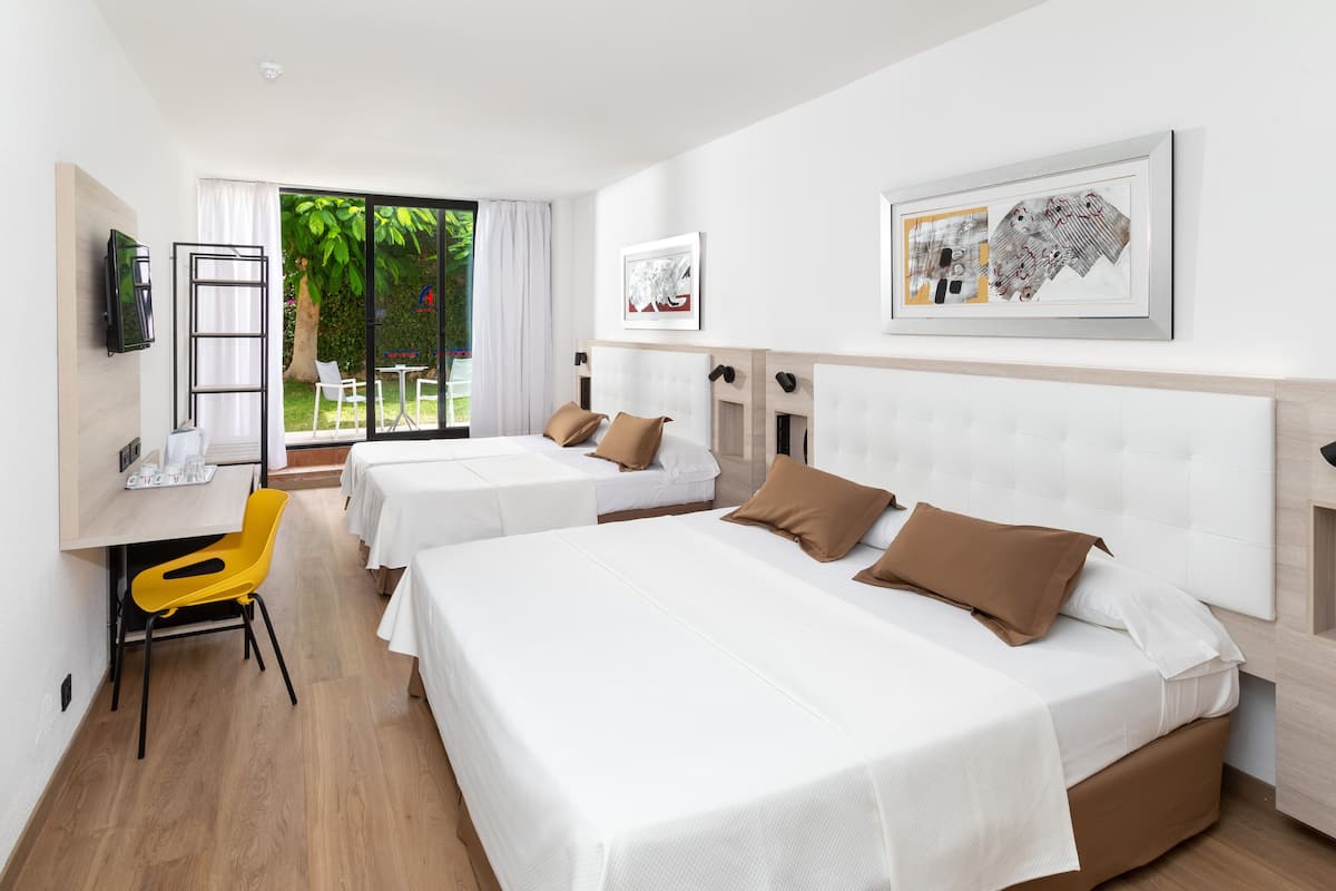 A hotel room with two beds, a desk, a chair, and a TV.
