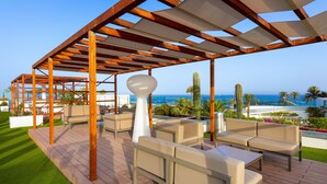Terraza de madera con mobiliario exterior y vista al océano.