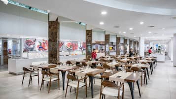Ein geräumiges Restaurant mit mehreren Tischen und Stühlen, einem zentralen Servicebereich und einem modernen Ambiente.