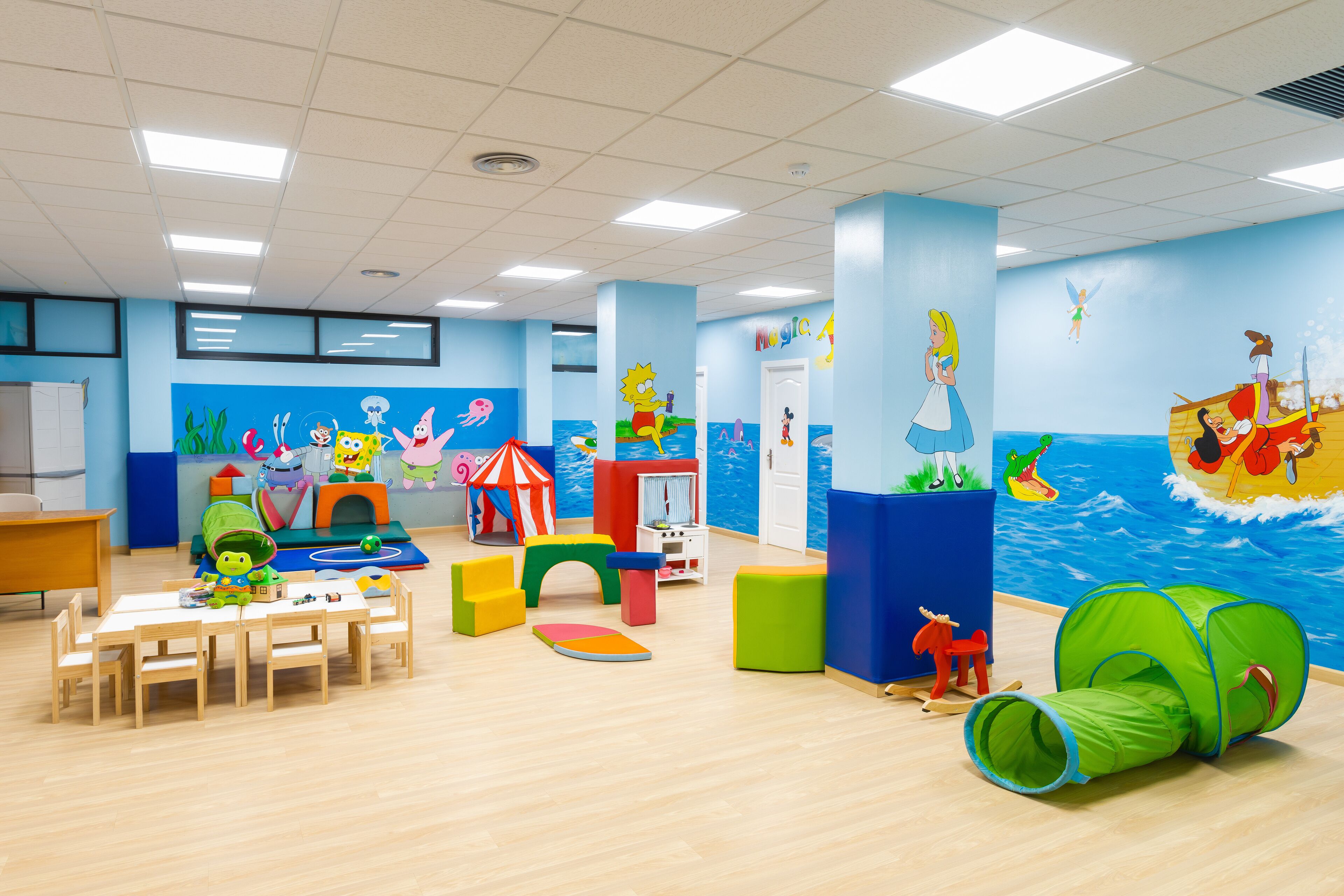 Een kinderspeelkamer met een nautisch thema, inclusief een muurschildering van zeedieren en een schip.