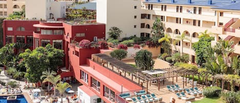 Um hotel com piscina no terraço, espreguiçadeiras e vista para a cidade.