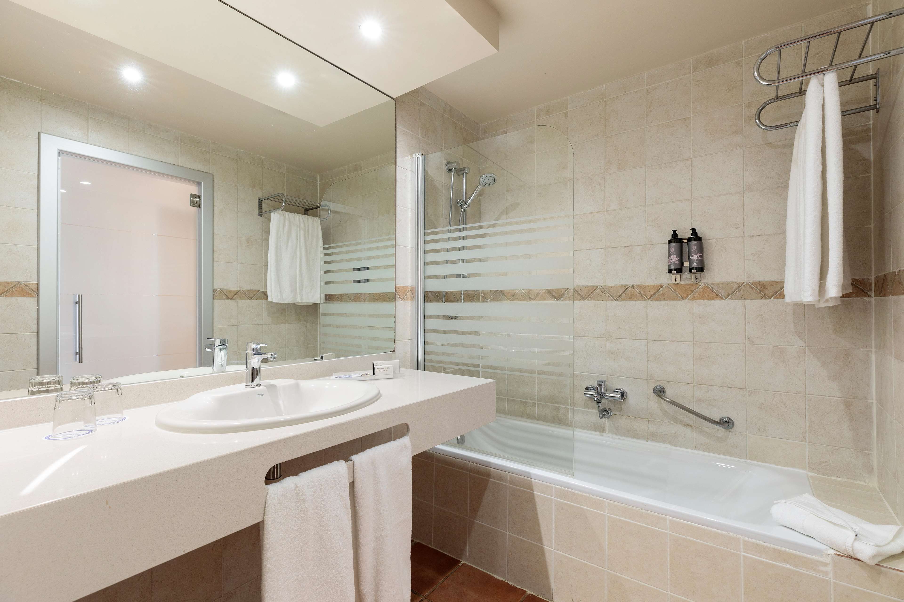 A modern bathroom with a double sink, a glass-enclosed shower, and a bathtub.