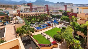 A hotel with multiple swimming pools, lush landscaping, and a view of mountains in the background. - Hotel Best Jacaranda (Adeje)