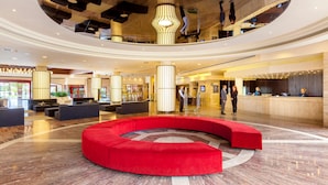 A spacious lobby with a central red seating area, a reception desk, and a high ceiling with unique lighting fixtures. - Hotel Best Jacaranda (Adeje)