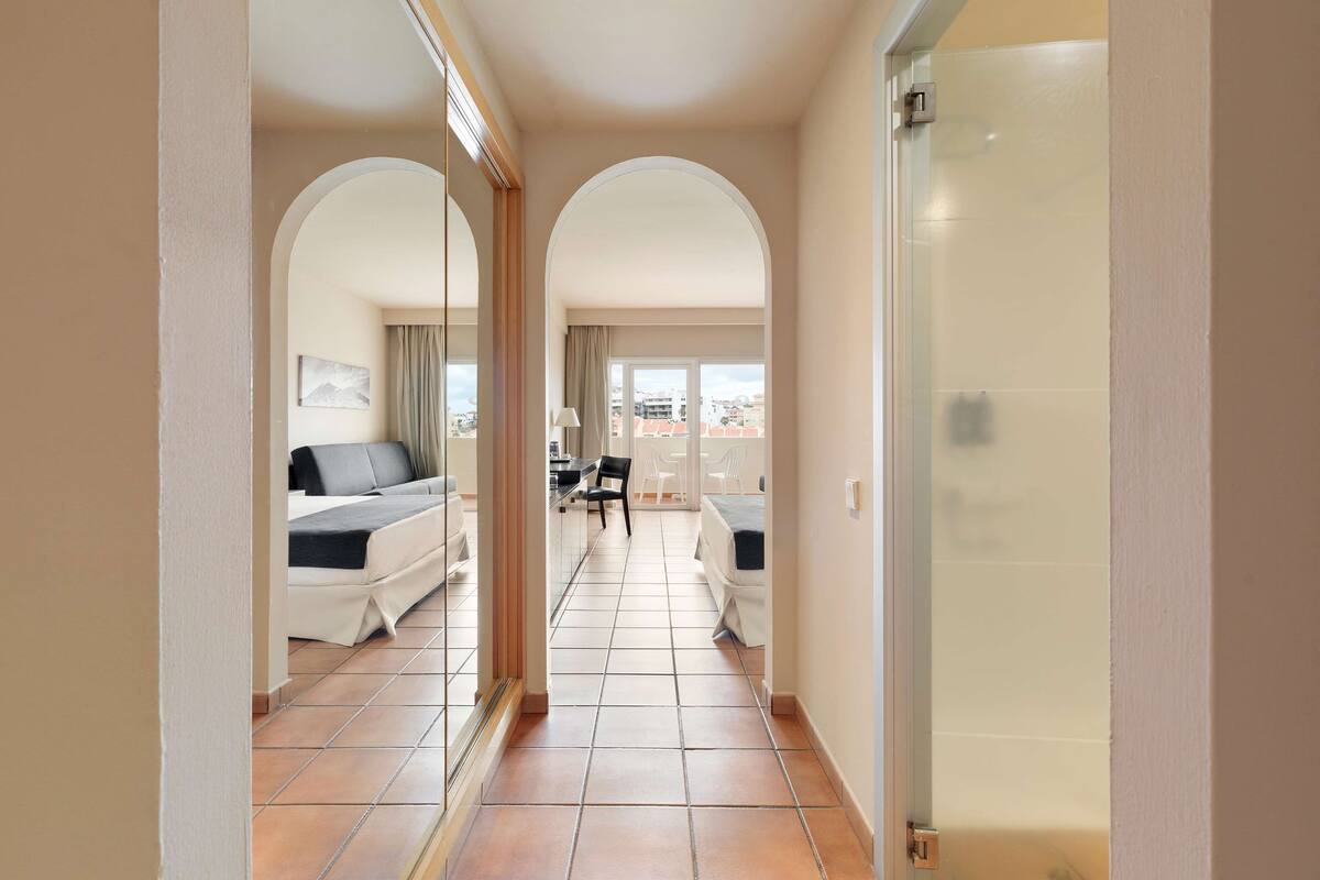 Un pasillo de hotel con arcos que dan a un dormitorio y un área de balcón.