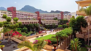 A hotel courtyard with a pool, lush greenery, and a view of mountains. - Hotel Best Jacaranda (Adeje)