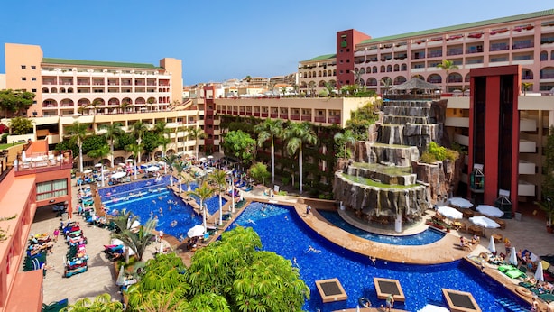A resort with multiple swimming pools, a central waterfall feature, and surrounding palm trees. - Hotel Best Jacaranda (Adeje)