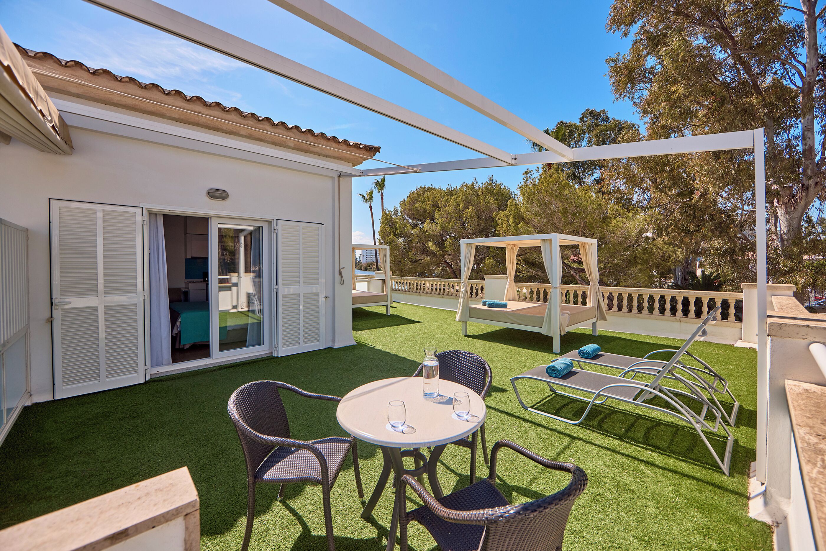 Un patio couvert avec une table et des chaises, une pergola et une vue sur les environs.