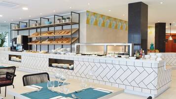 Un restaurante moderno con una barra central, varias áreas de estar y una pared decorativa.