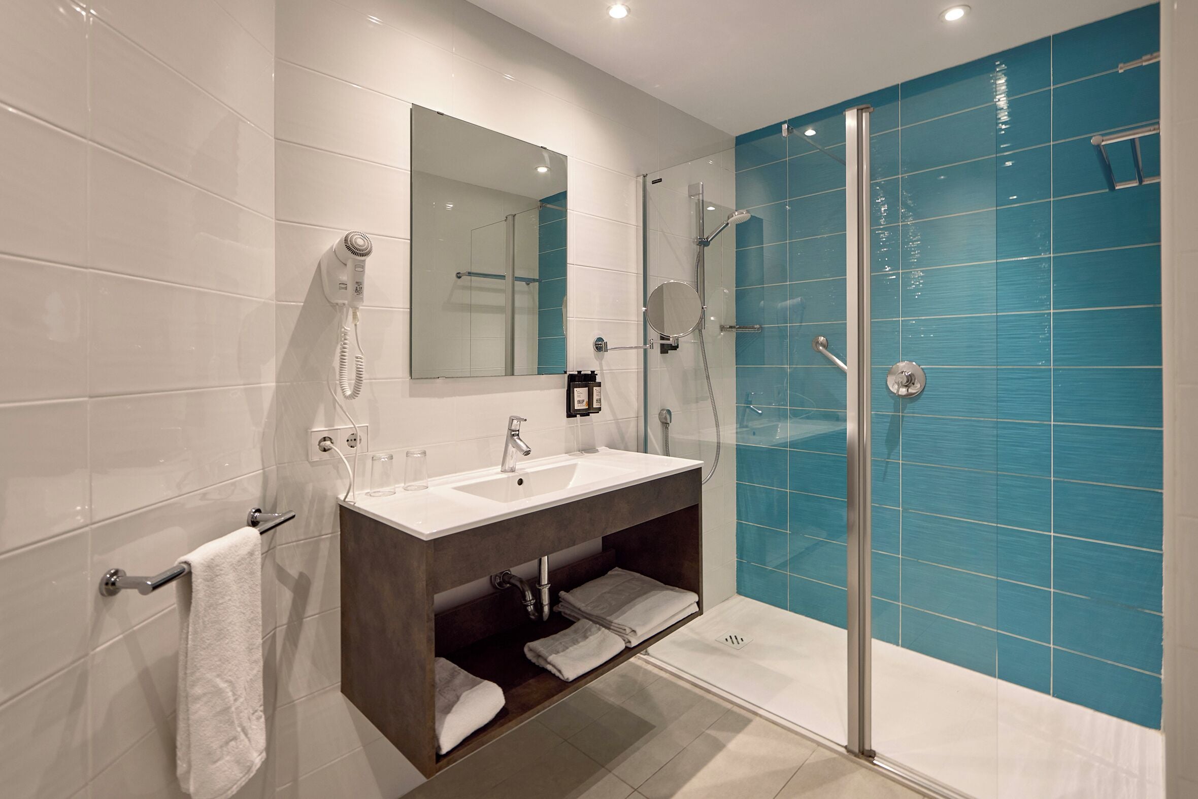 Une salle de bain moderne avec une douche à parois de verre, un lavabo blanc et un grand miroir.